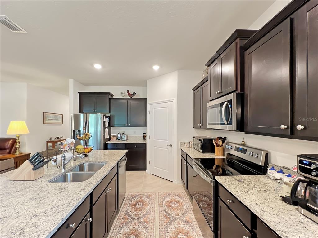 6265 Southwest 88th Loop Ocala, FL 34476 - Photo 30 of 42 a kitchen with stainless steel appliances granite countertop a sink stove and refrigerator