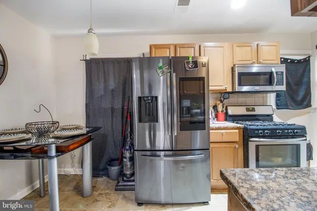 a kitchen with stainless steel appliances granite countertop a refrigerator stove top oven and sink