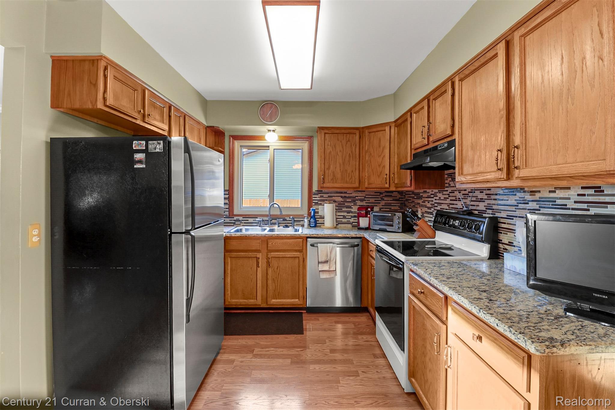 2867 Dearborn Avenue Rochester, MI 48309 - Photo 6 of 25 Kitchen featuring stainless steel appliances, tasteful backsplash, light wood-style floors, light stone counters, and brown cabinetry