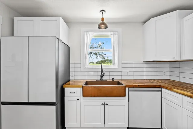 a kitchen with a sink a refrigerator a window and cabinets