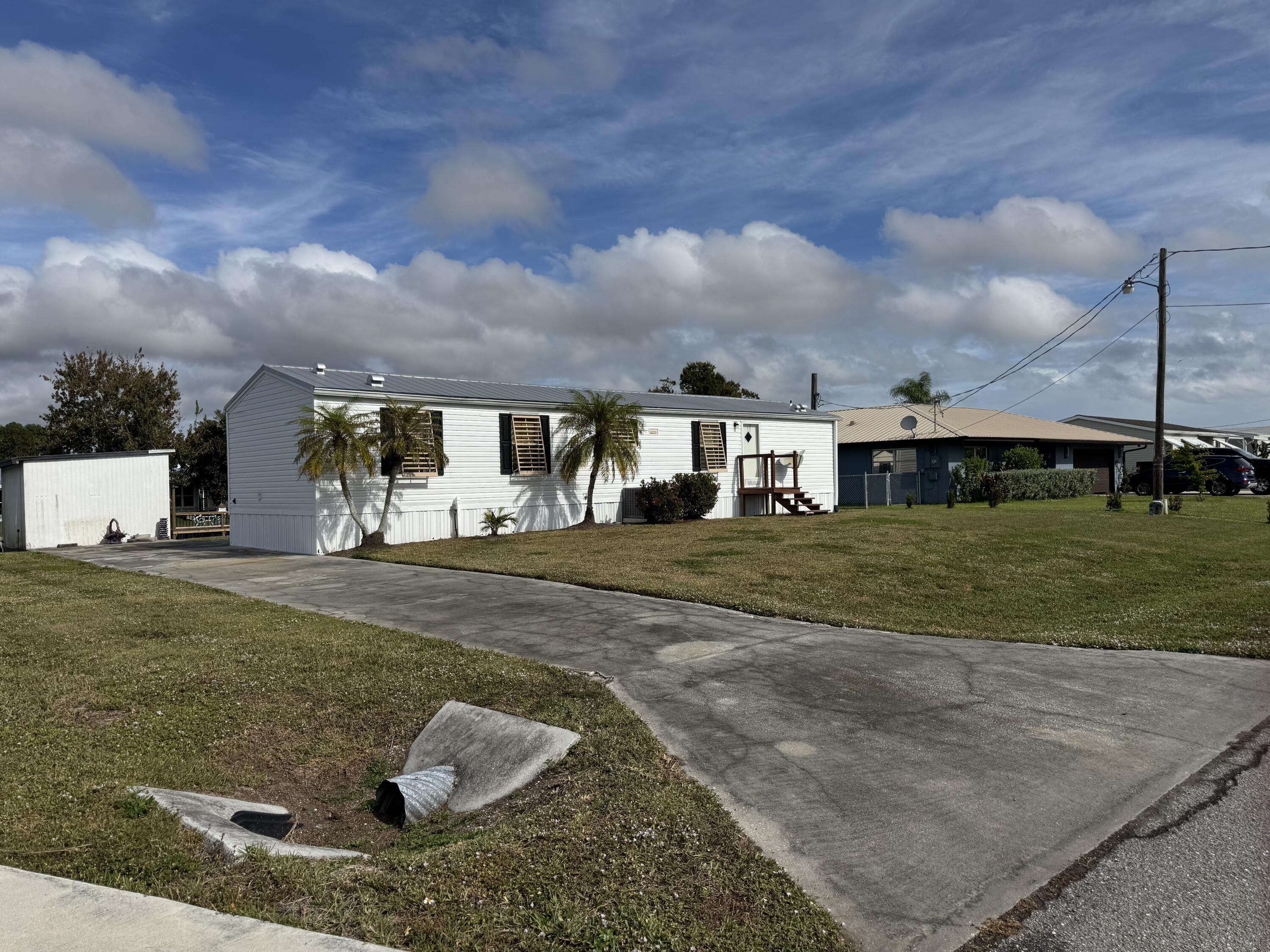2305 Southeast 31st Street Okeechobee, FL 34974 - Photo 29 of 30 a view of a white house in front of a big yard with plants and large tree