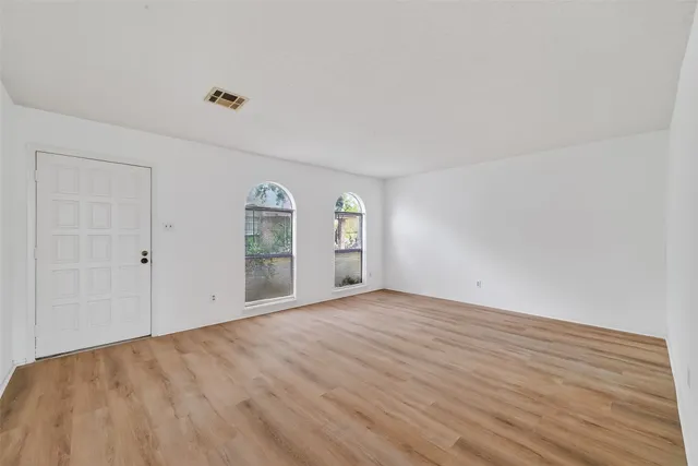 a view of an empty room with window and wooden floor