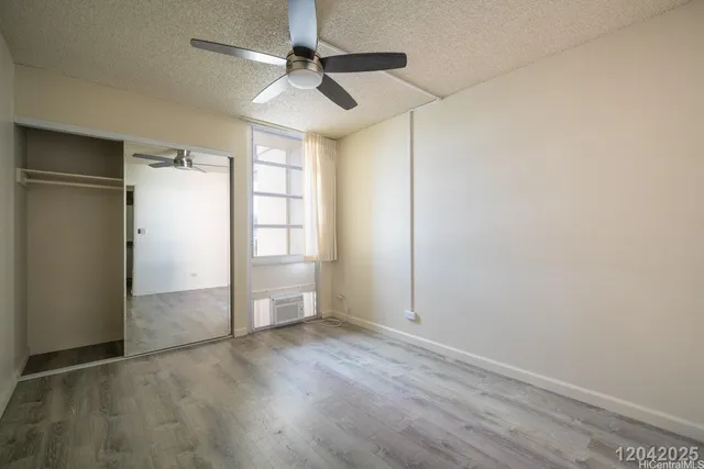 an empty room with wooden floor cabinet and windows