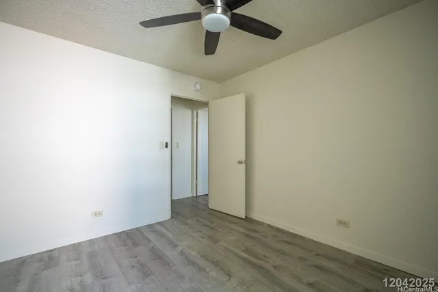 an empty room with wooden floor ceiling fan and window