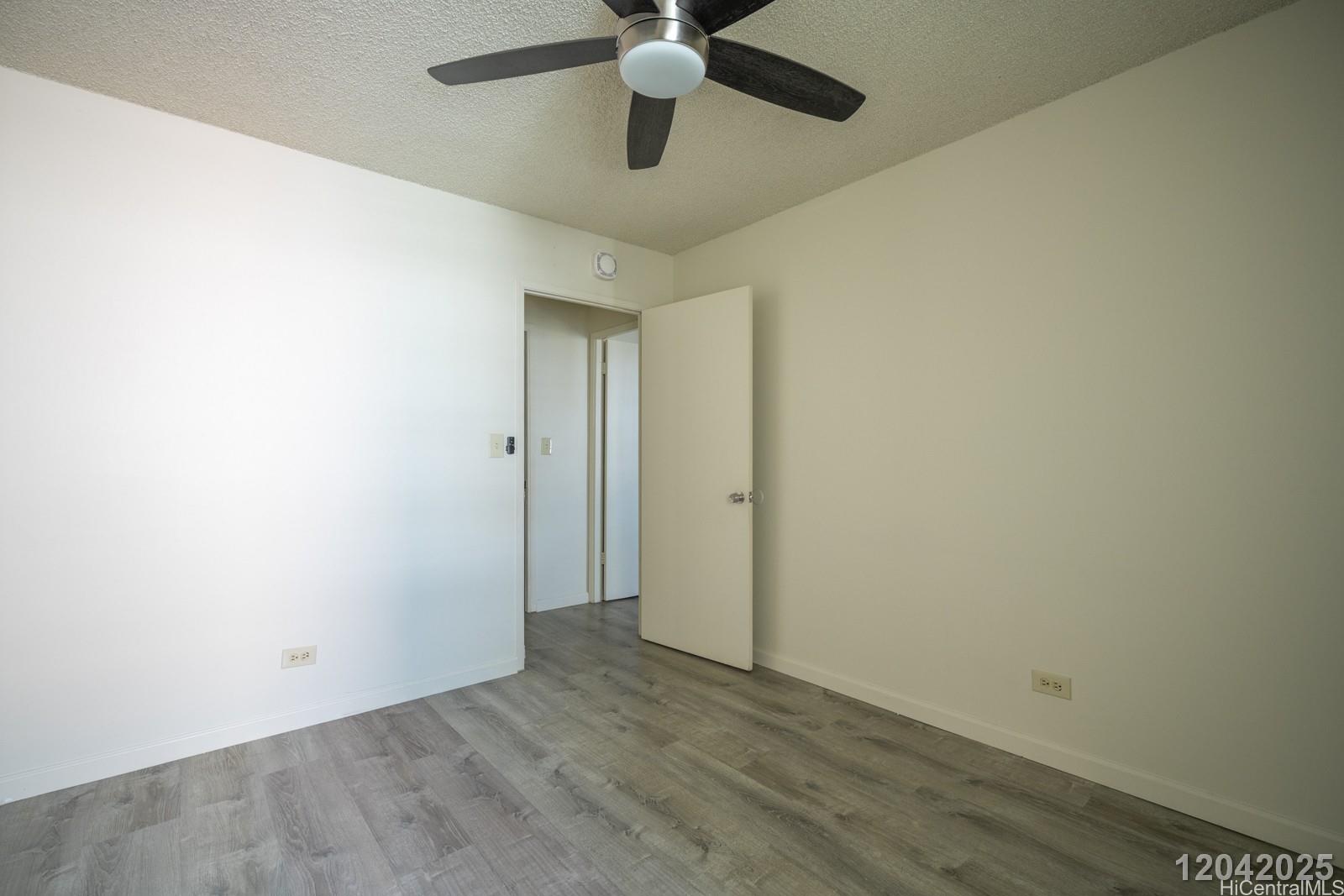 3161 Ala Ilima Street, Unit 1403 Honolulu, HI 96818 - Photo 15 of 24 an empty room with wooden floor ceiling fan and window