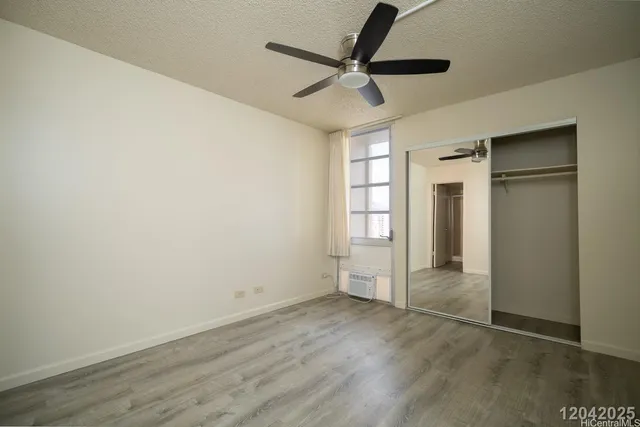 an empty room with wooden floor closet and windows