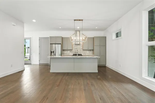 a large kitchen with stainless steel appliances granite countertop a large counter top and wooden floors