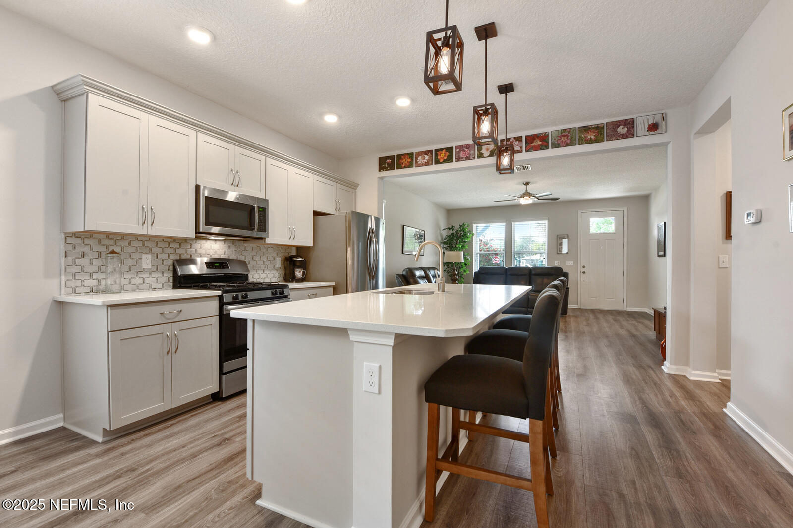 134 Jackrabbit Trail Ponte Vedra, FL 32081 - Photo 14 of 26 a kitchen with stainless steel appliances kitchen island granite countertop a sink a microwave a stove and white cabinets with wooden floor