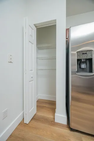 a view of a hallway with wooden floor and closet