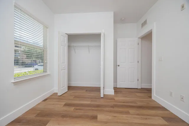 a view of an empty room with wooden floor and a window