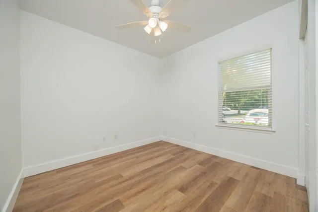 an empty room with a window and a ceiling fan
