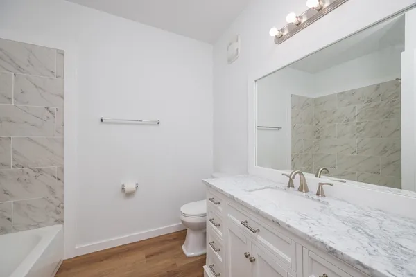 a bathroom with a granite countertop sink a toilet and shower