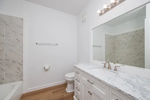 a bathroom with a granite countertop sink a toilet and shower