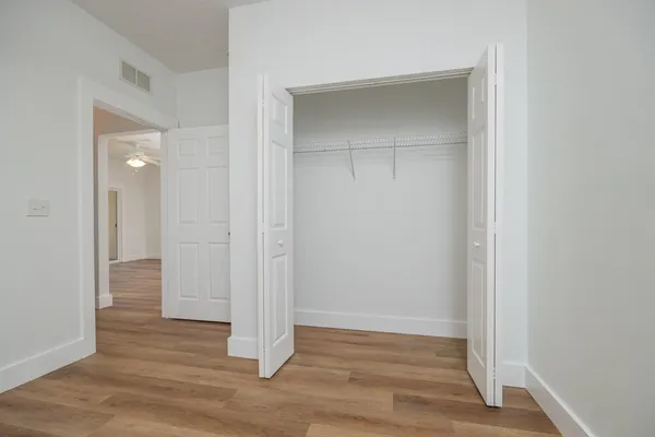 an empty room with wooden floor & closet area