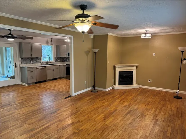a view of an empty room with window and wooden floor