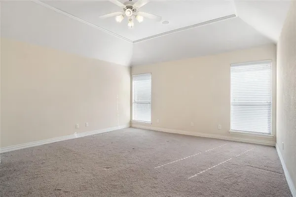 an empty room with a chandelier fan and windows