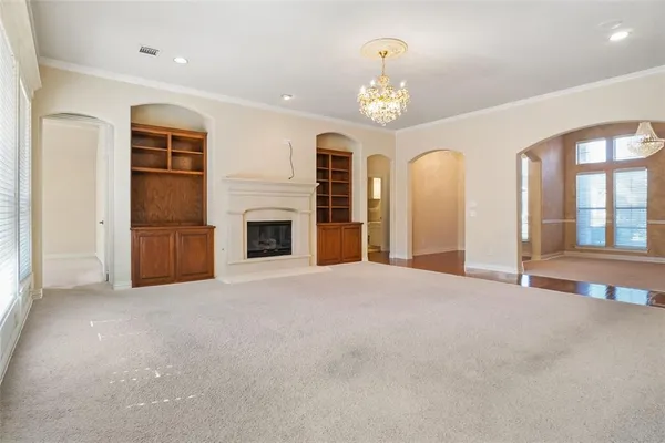 an empty room with fireplace chandelier and windows