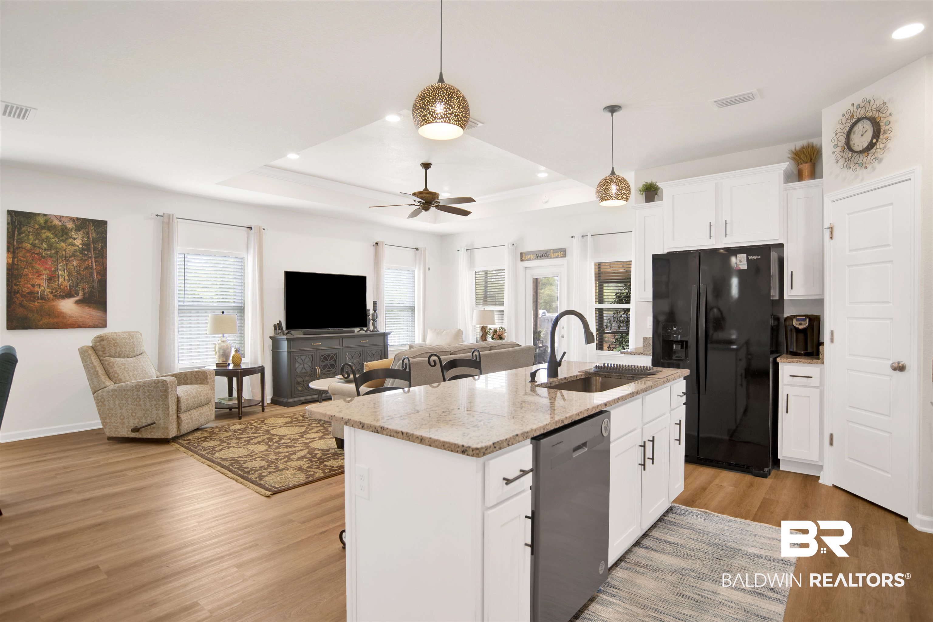 13778 Antler Hl Road Daphne, AL 36527 - Photo 36 of 38 Kitchen with white cabinets, open floor plan, a kitchen bar, light stone counters, and black fridge with ice dispenser