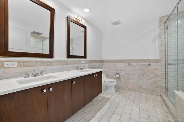 a bathroom with a double vanity sink mirror and toilet