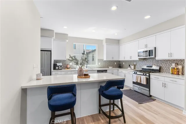 a kitchen with stainless steel appliances granite countertop a stove a sink dishwasher and a microwave oven with white cabinets