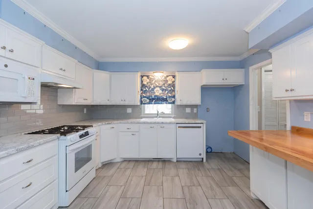 a kitchen with granite countertop white cabinets and white appliances
