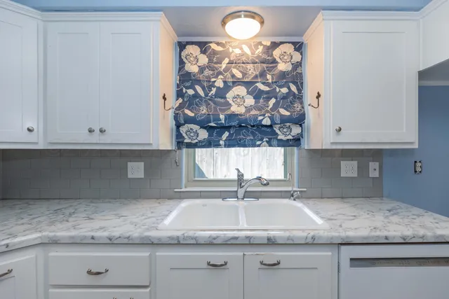 a kitchen with granite countertop white cabinets and a sink