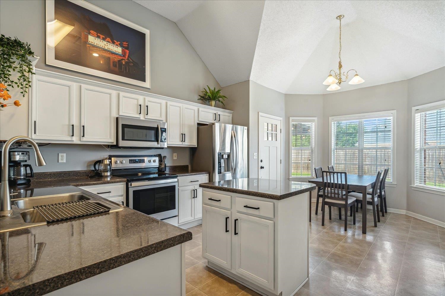 5003 Will Fall Lane Bartlett, TN 38002 - Photo 9 of 26 a kitchen with stainless steel appliances granite countertop a stove top oven a sink dishwasher a dining table and chairs with wooden floor