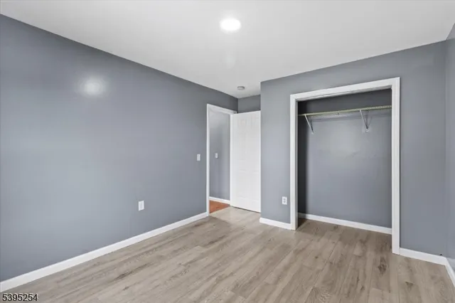a view of an empty room with wooden floor & closet