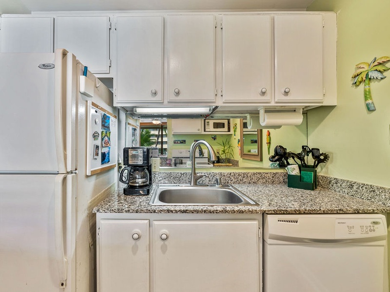 75-5870 Kahakai Road, Unit 409 Kailua-Kona, HI 96740 - Photo 8 of 16 a kitchen with granite countertop a refrigerator a stove and a sink