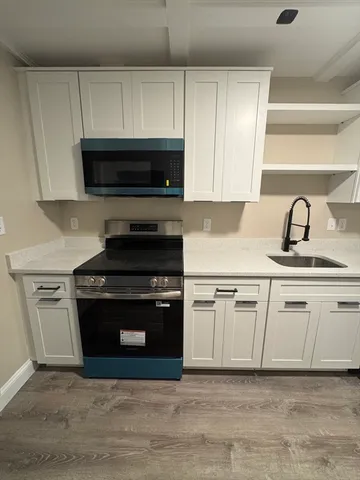 a kitchen with granite countertop a sink dishwasher a stove and a microwave oven with cabinets