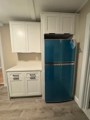a close view of a refrigerator in kitchen and white cabinets