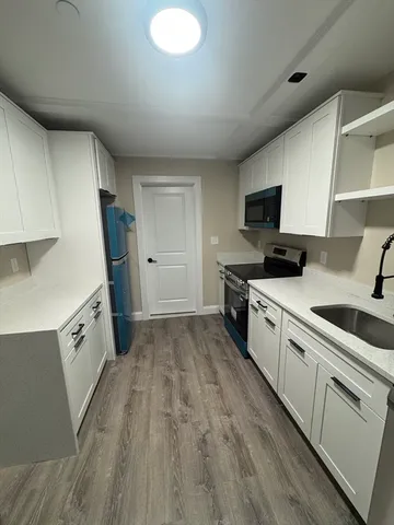 a kitchen with granite countertop a stove top oven a sink dishwasher and a refrigerator with wooden floor