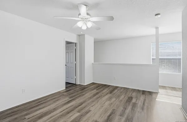 an empty room with wooden floor and fan
