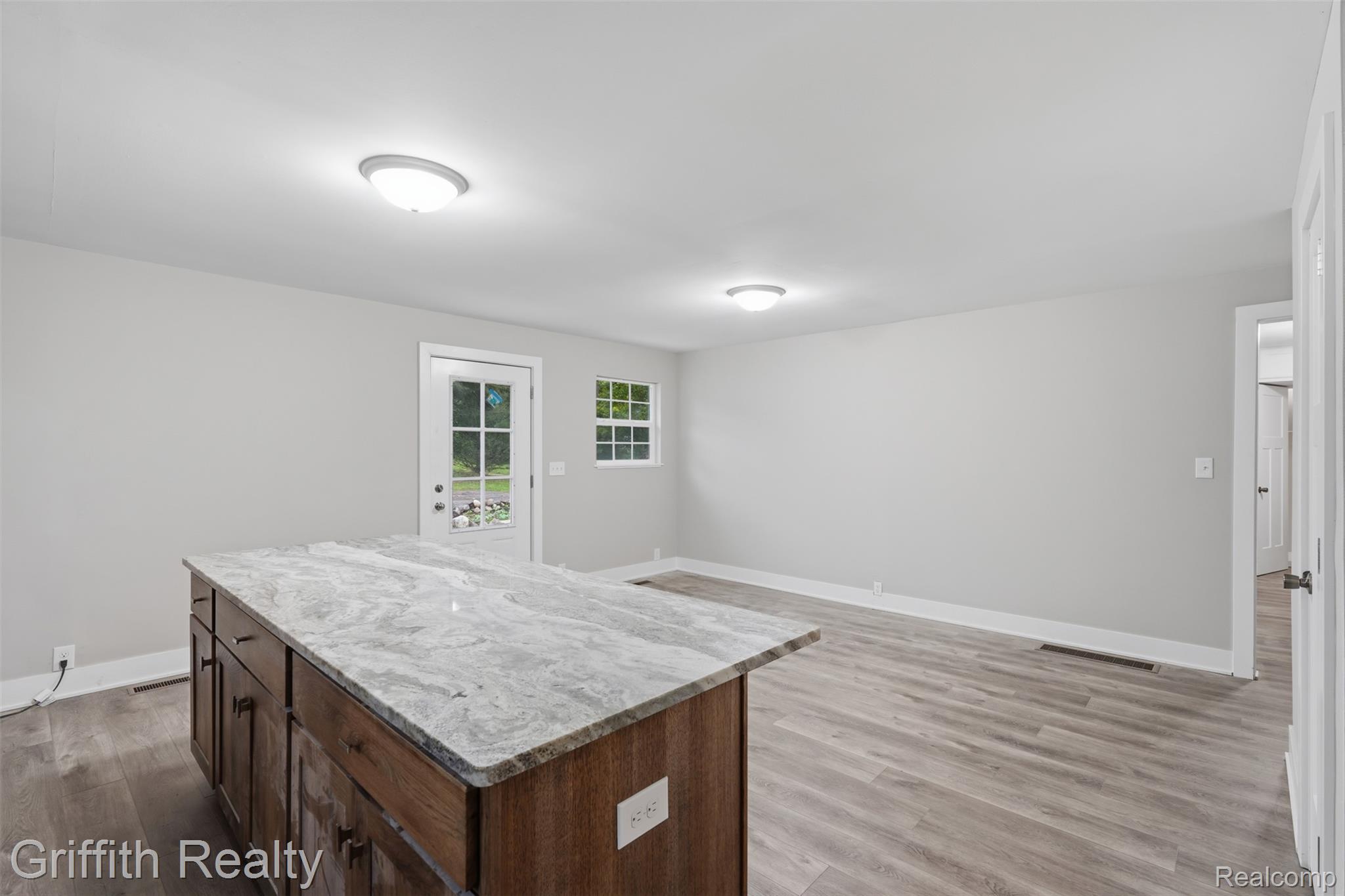 5820 Mack Road Howell, MI 48855 - Photo 14 of 60 Kitchen island with stone countertop, wood-finish cabinetry, and dark hardware