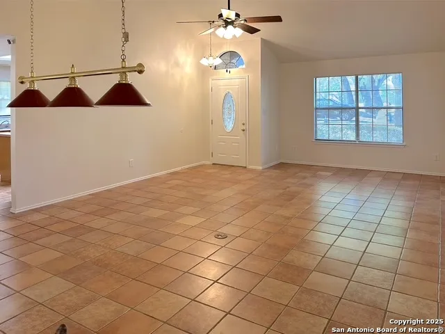 an empty room with windows and ceiling fan