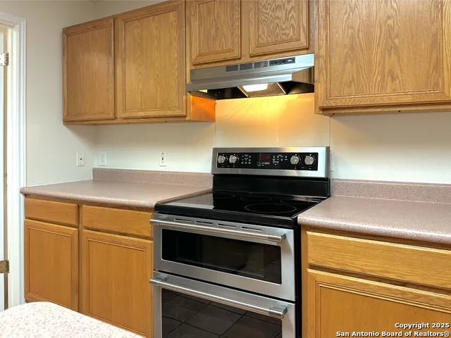 a kitchen with wooden cabinets and a stove top oven