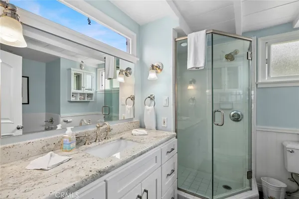a bathroom with a granite countertop sink shower mirror and toilet