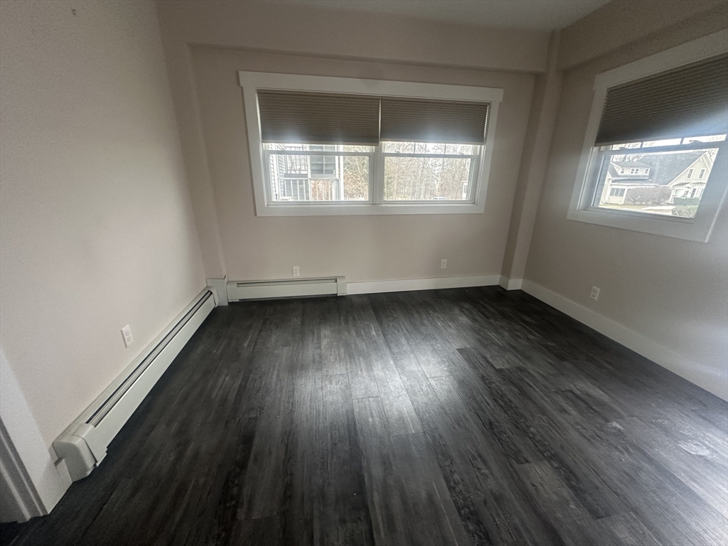 105 Elm Street, Unit 1 Gardner, MA 01440 - Photo 8 of 9 an empty room with wooden floor and windows