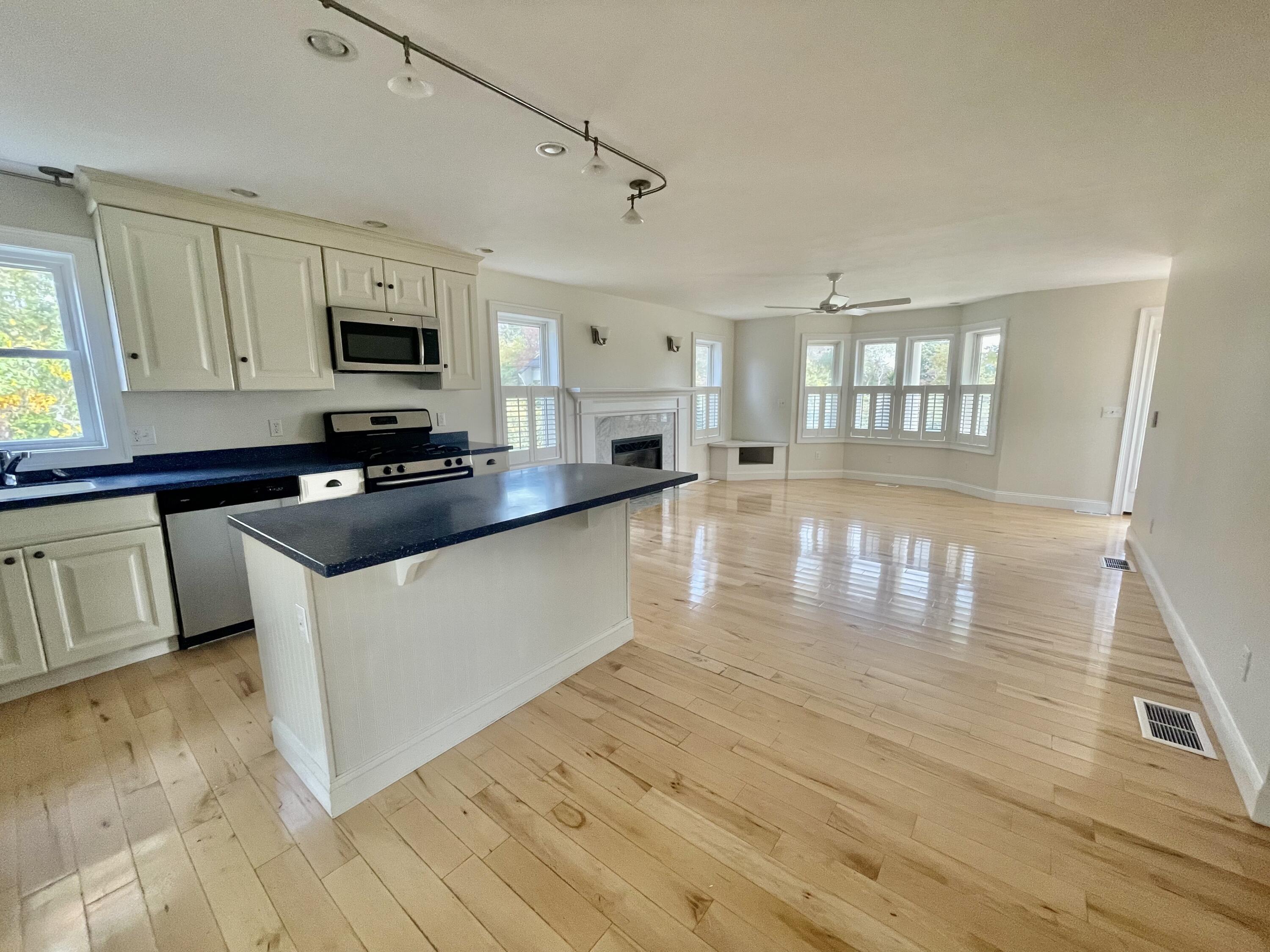 215 Harbor Point Road Barnstable, MA 02675 - Photo 4 of 10 a kitchen with granite countertop a stove top oven a sink dishwasher and white cabinets with wooden floor
