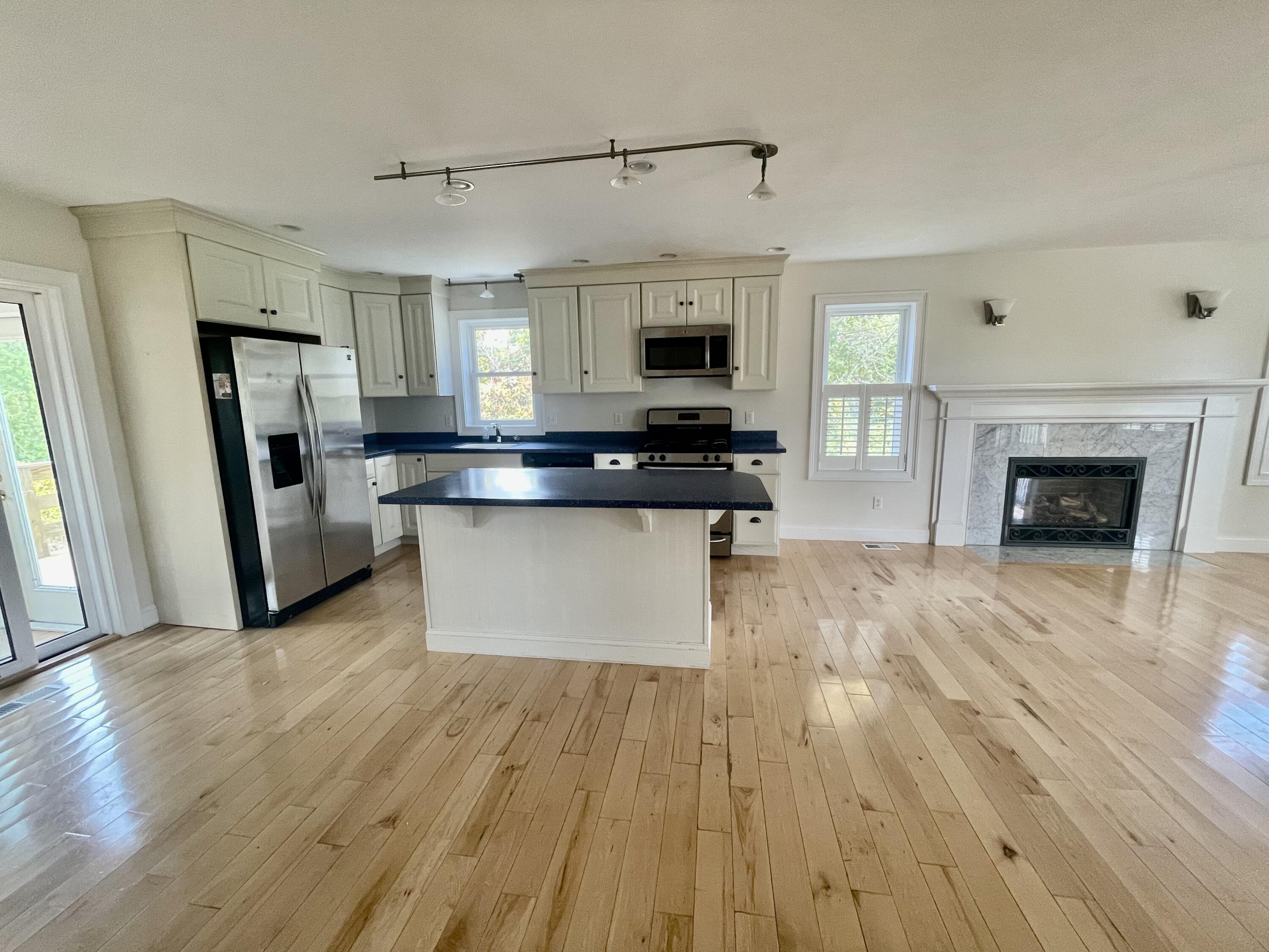 215 Harbor Point Road Barnstable, MA 02675 - Photo 5 of 10 a kitchen with stainless steel appliances a stove top oven a sink dishwasher a refrigerator and a fireplace with wooden floor