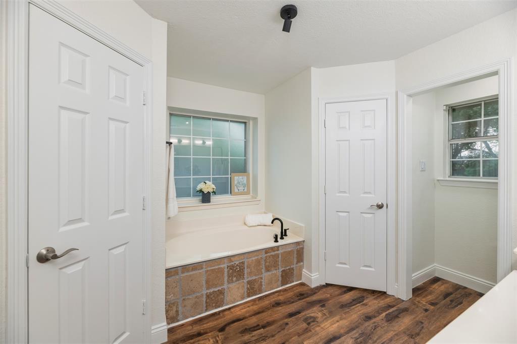 215 Barbara Way Red Oak, TX 75154 - Photo 19 of 36 Soaking bath in ensuite primary bath is the perfect place to relax and unwind after a busy day. Split bedrooms offers additional privacy.Updated bathroom with clean, fresh finishesThe bathroom offers a bright, refreshed look with a modern vanity, updated flooring, and neutral finishes. A practical space that feels clean, simple, and move-in ready.The primary bathroom offers a soaking tub to relax and unwind after a busy day.