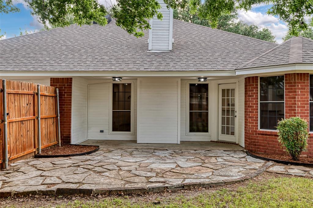 215 Barbara Way Red Oak, TX 75154 - Photo 32 of 36 Covered back patio ready for outdoor living — the flagstone-style surface and private setting offer a strong foundation for creating a cozy backyard retreat.