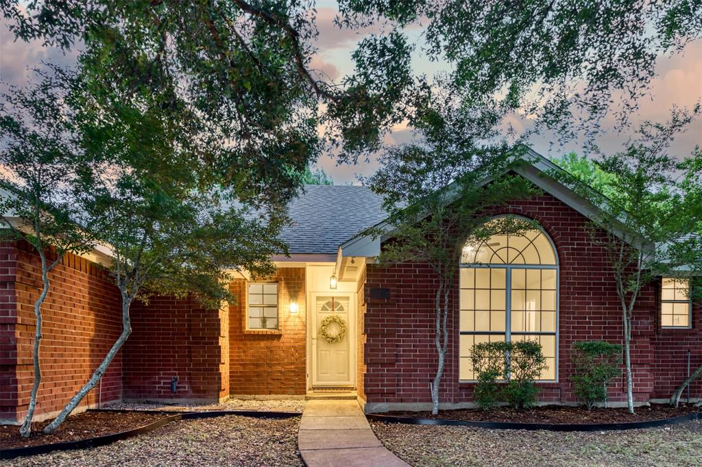 215 Barbara Way Red Oak, TX 75154 - Photo 4 of 36 Twilight exterior view highlights the home’s charm, with inviting light, arched windows, and a timeless brick façade.