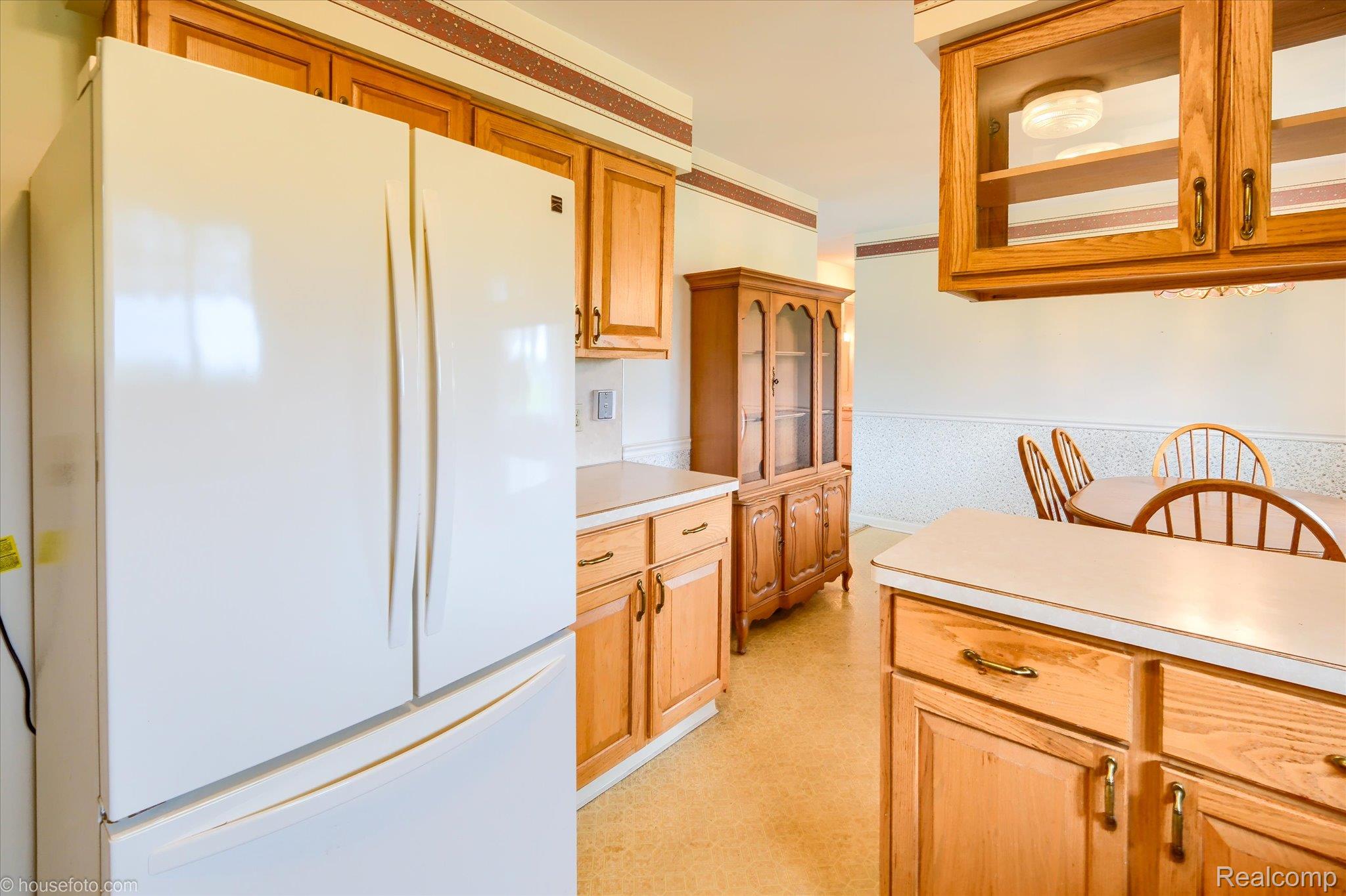 6080 Shattuck Road Saginaw, MI 48603 - Photo 18 of 35 Kitchen with freestanding refrigerator, glass insert cabinets, light countertops, and wood finish cabinetry