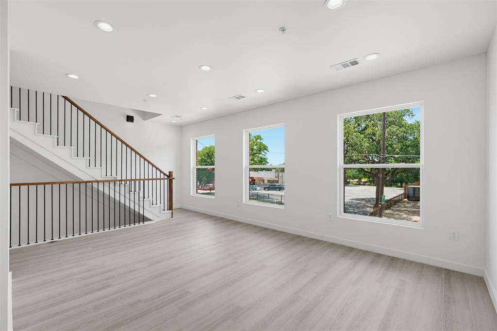 512 South O Connor Road Irving, TX 75060 - Photo 3 of 21 Expansive open-concept living area featuring wood-finish flooring, recessed lighting, and a modern staircase with dark metal balusters and wood handrails