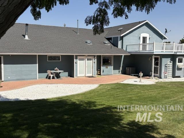 11603 West Hidden Valley Rim Road Boise, ID 83709 - Photo 2 of 4 Expansive lawn with a brick paver patio, gravel landscaping, and a second-story balcony with white railings