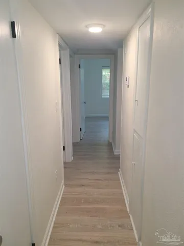 a view of a hallway with wooden floor and closet
