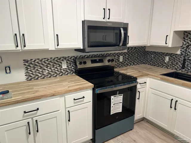 a kitchen with granite countertop white cabinets and black stove top oven with granite countertops