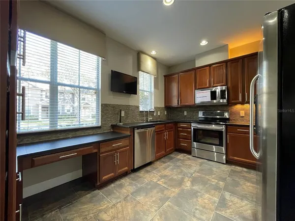 a kitchen with granite countertop a refrigerator and a stove top oven