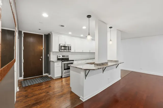a kitchen with a refrigerator and wooden floor